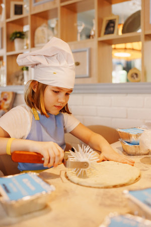Young chef prepares pizza dough in cozy kitchen settingの写真素材