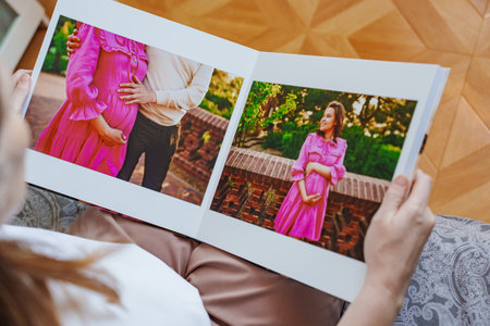 woman is holding and flipping through a photo book with a pregnancy photo shootの写真素材