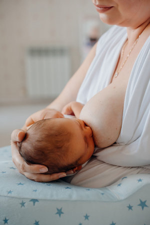 Mother breastfeeding baby indoors in soft light