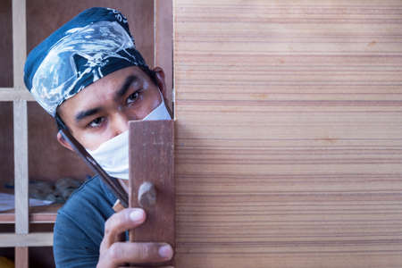 Young male carpenter take a planer with wood in workshopの写真素材