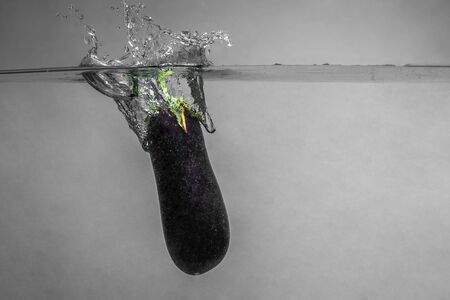 Ripe eggplant with splashes tossed into clean water.の写真素材