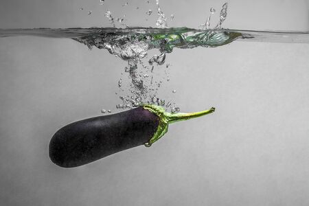 Ripe eggplant with splashes tossed into clean water.の写真素材