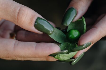 girl with green manicure holds a green cranberry in her handsの写真素材