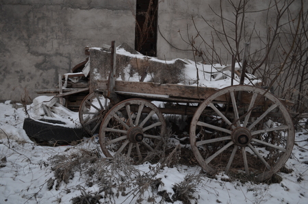 cart, wagon, dray, wain with big huge wooden wheels in snow in winterの写真素材