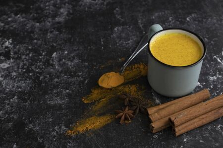 golden milk with cinnamon in a blue ceramic cup with cinnamon sticks and star anise in the background, a healthy drink for immunity, virus control, copy spaceの写真素材