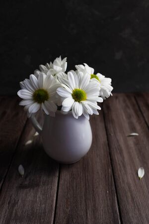 white chrysanthemums in a milkman on a wooden background, beauty concept, floral mood, vertical orientation, copy spaceの写真素材