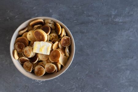 Tiny pancakes, small pancakes with butter and honey, on a concrete background in a bowl, flat layの写真素材