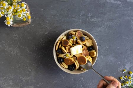 Trend 2020, tiny pancakes with berries, small pancakes, quarantine breakfast, homemade food, A female hand takes a tiny pancake with a spoonの写真素材