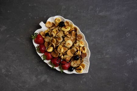 trendy food, Tiny pancake cereal with strawberries and chocolate, quick tasty breakfast on a gray backgroundの写真素材