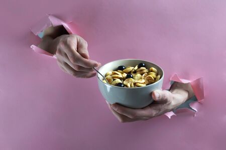 male hands pick up tiny pancakes with a spoon through a hole in a paper wall, horizontal orientation, trendy food - small pancakes with berriesの写真素材