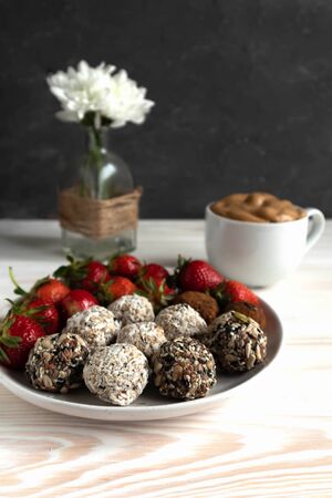 energy balls or prothin balls, healthy sweets on a flat plate with strawberries and dalgona coffee- Korean drink, trend 2020, healthy breakfast conceptの写真素材