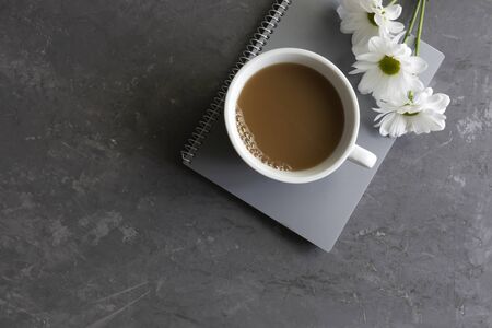 on a gray background notebook with a cup of coffee and white flowers, workplace, workspace concept, copy space
の写真素材