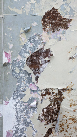 Old Wall with Peeling Blue and Brown Paint. Close-up of an aged wall with peeling blue and brown paint, revealing textured layers and weathered surface details.の写真素材