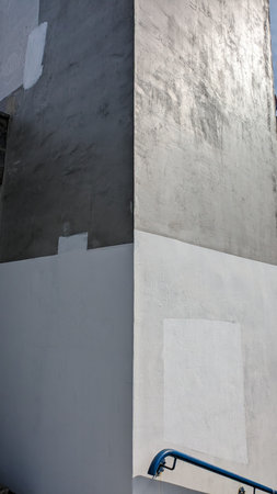Corner of White and Gray Wall with Blue Railings. Minimalist corner of a white and gray painted wall featuring blue metal railings, highlighting geometric shapes and color contrastの写真素材