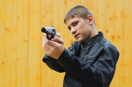 The teenager in black clothes aims from a pistol の写真素材