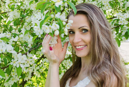 Portrait of beautiful  woman with apple tree flowers in the  park