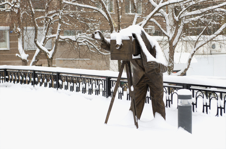 The sculpture "photographer" in city park in the winter, under snowの写真素材