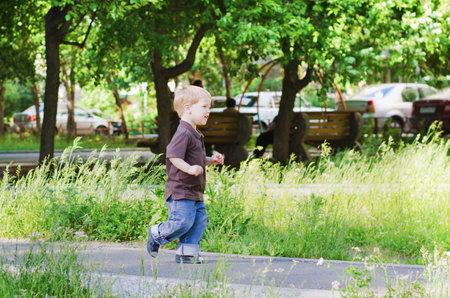 The child runs on avenue in a summer gardenの写真素材