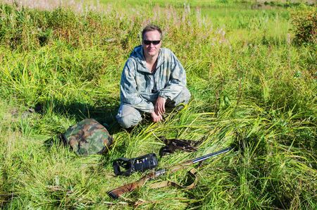 Happy hunter sitting on the grass next to the prey on a warm Sunny autumn dayの写真素材