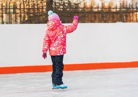 Happy girl skating on the ice rink evening at sunsetの写真素材