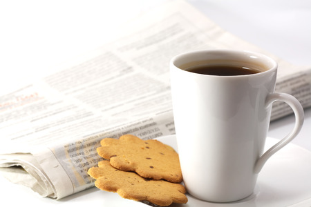 cup of tea on dish with cookies and newspaperの写真素材