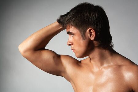 close-up portrait of young naked muscular athlete; isolated on grayの写真素材