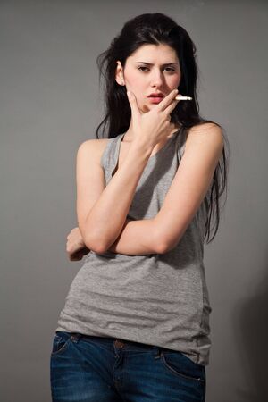fashion style photo of a beautiful young brunette woman holding a cigaretteの写真素材