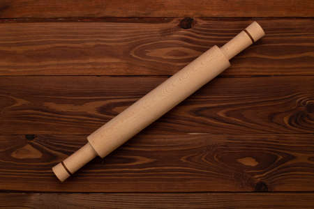 Traditional handmade organic wooden culinary dough rolling pin for cooking on a brown background with wooden texture. Kitchenware. Top view, Close Upの写真素材