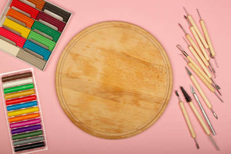 Plasticine modeling tools kit on a pink background. Wooden desk in the classroom for lessons with...
