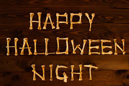 Lettering from the bones of the words Happy Halloween Night on a beautiful dark brown wooden...