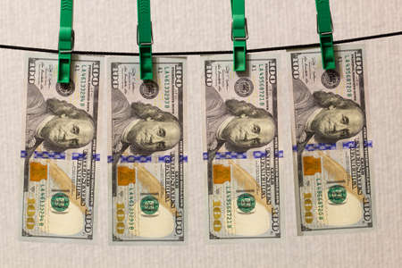 Money laundering. Laundering of money. The concept of laundering corruption criminal money. Hundred dollar American bills hang on a clothesline. US dollars banknotes are dried after washingの写真素材