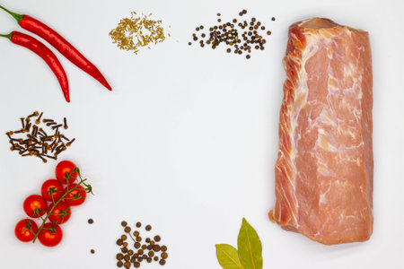Meat and spices. Isolated. Large piece of meat, red hot chili pepper, cherry tomatoes, cumin, black peppercorns, cloves, bay leaf, dried spices on white background. Copy space forの写真素材