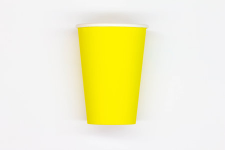 Paper coffee cup. Yellow craft paper coffee cup without lid. Disposable cup for safe drinking of hot and cold drinks. Safe ribbed capacity. Container for healthy beverage. Isolatedの写真素材