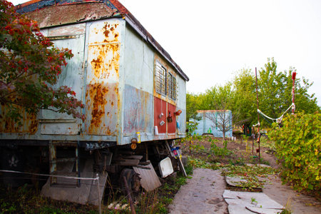 Post-apocalyptic housing. Old trailer in the forest. An antique wagon in an orchard among trees and bushes. Mechanisms and devices for scaring away from animals and birdsの写真素材