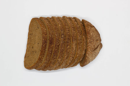 Sliced black bread. Dark rye bread with cumin cut into even pieces on a white background. Wheat black bread on the table. Isolated. Bran from grain. Healthy food. Vegetarian food.の写真素材