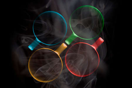Four cups of different colors are filled with a hot drink. A thick white vapor rises above them. Illuminated upper circuit. View from above. Isolated on black. Copy space to add your text.の写真素材