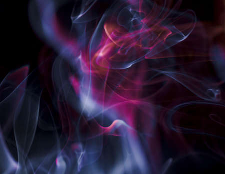 Thick, scenic clouds of smoke. From incense, or cigarettes, or cigars. Indoors. In the rays of sunshine on a dark background. Psychedelic mood. Close up. Colorful abstract background.の写真素材