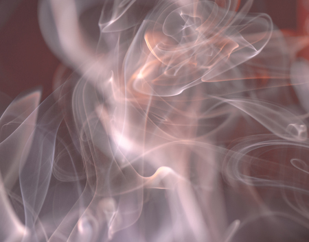 Thick, scenic clouds of smoke. From incense, or cigarettes, or cigars. Indoors. In the rays of sunshine on a dark background. Psychedelic mood. Close up. Colorful abstract background.の写真素材