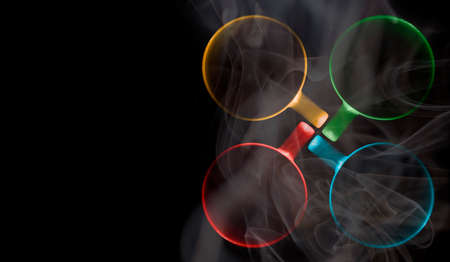 Four cups of different colors are filled with a hot drink. A thick white vapor rises above them. Illuminated upper circuit. View from above. Isolated on black. Copy space to add your text.の写真素材