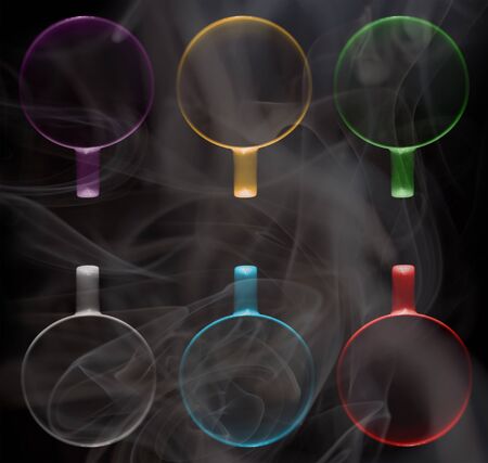 Six cups of different colors are filled with a hot drink. A thick white vapor rises above them. Illuminated upper circuit. View from above. Isolated on black. Copy space to add your text.の写真素材