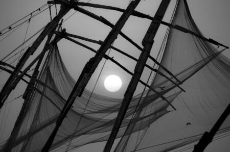 Chinese fishing nets on the shore of the Arabian Sea. Fort Cochin, Kerala, India. Historic Landmark. Warm evening. Scenic contours in the sunset twilight. Bright solar disk. Delicate juicy colors.の写真素材