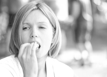 Portrait of young intelligent pretty woman. With an appetite, she eats a sandwich.  She is glad and happy. Summer picnic in forest. Closeup, natural lighting and a blurred background. Black & white.の写真素材