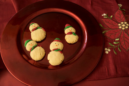 Red and green snowmen butter cookies on red mosaic glass dishの写真素材