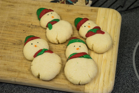 Snowmen butter cookies on bamboo cutting boardの写真素材