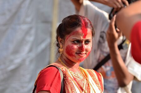 Portrait of young lady with red colour on face during celebration of last day of Durga Puja festivalのeditorial素材