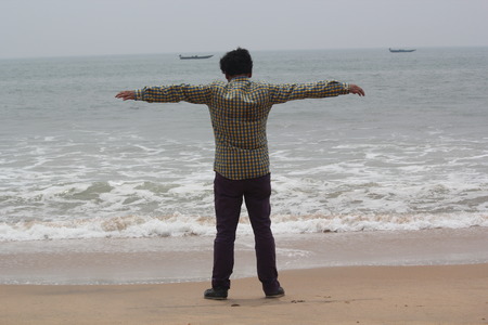 Man stretched his arms in freedom on the background of beachの写真素材