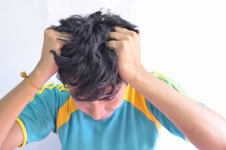 Young man tearinh his hairs with griefの写真素材