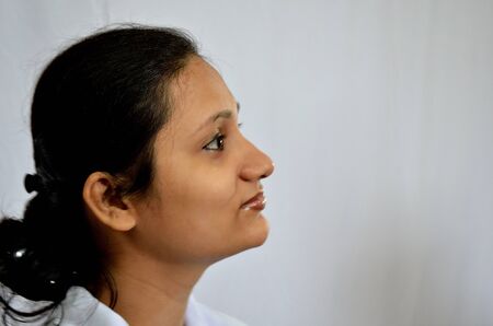 Girl thinking with smiling in a white backgroundの写真素材