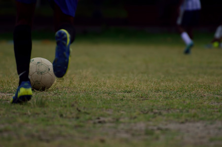 Boy is playing soccer in a ground. Football in motion is captured. Motion of leg is captured.の写真素材