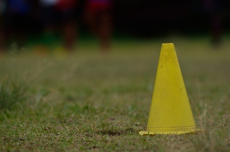 Yellow cone on green grass during practice sessionの写真素材